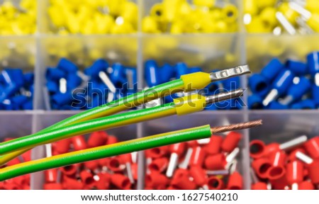 Insulated cord pin end terminals on green electric conductors detail. Stripped copper wire or yellow crimped power cable connectors. Colored joining ferrules organized in plastic box. Selective focus. Royalty-Free Stock Photo #1627540210
