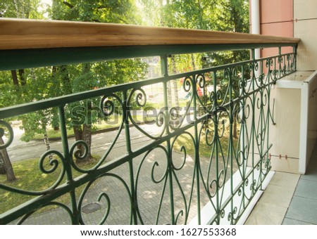 View from a modern balcony through a metal openwork wrought iron fence with railings to the Park on a Sunny summer day Royalty-Free Stock Photo #1627553368