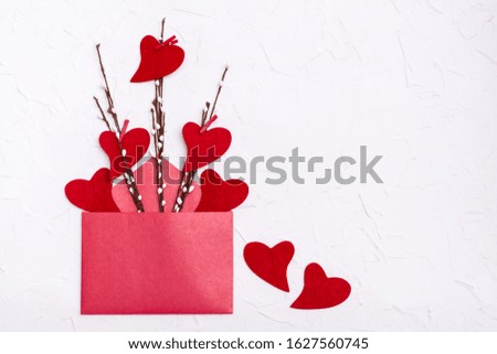 Valentine's Day. Red hearts made of felt on willow branches  in an open red envelope and near on a white background. Copy space