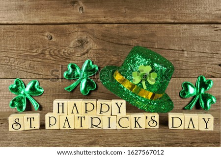Happy St Patricks Day wooden blocks with shiny shamrocks and leprechaun hat on a wooden background