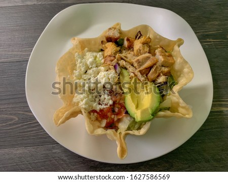 A grilled chicken salad bowl. Salad in a fried tortilla shell.