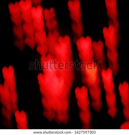 Blurry glowing luminous silhouettes of hearts. red on black