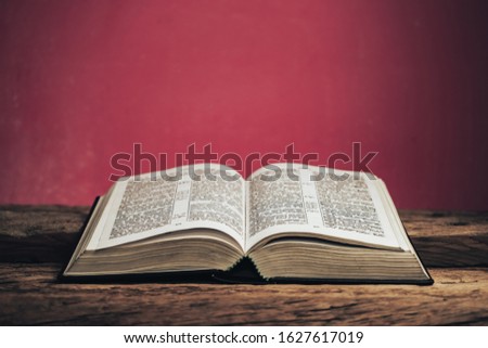 Open bible on a old oak wooden table. Beautiful green wall background.