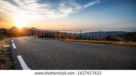 Empty long mountain road to the horizon on a sunny summer day at bright sunset Royalty-Free Stock Photo #1627617622