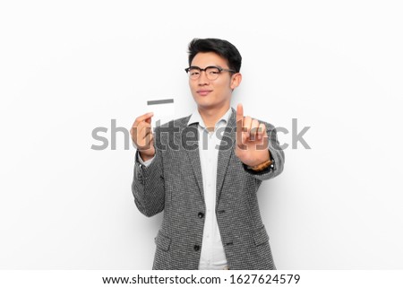 young japanese man smiling proudly and confidently making number one pose triumphantly, feeling like a leader. credit card concept.