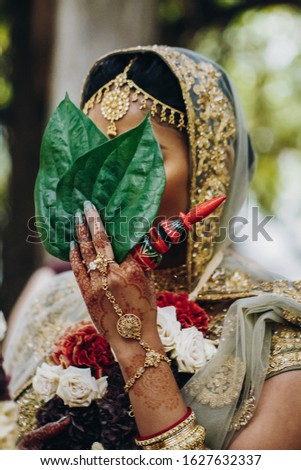 Indian bride with closed face in traditional wedding outfit, bridal accessories