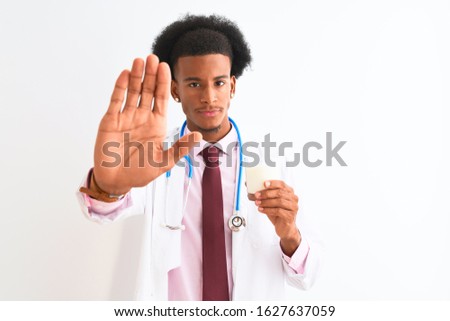 Young african american doctor man drinking glass of milk over isolated white background with open hand doing stop sign with serious and confident expression, defense gesture