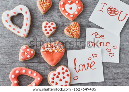 Deocrated heart shape cookies and paper sheets with inscriptions be mine, love and i love you on gray background. Valentines Day concept