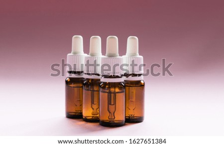 cosmetology, glass bottles with pipettes and cosmetic on a pink background
