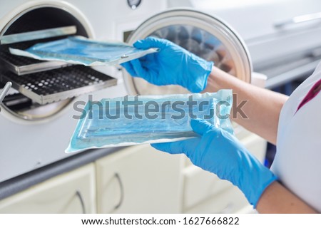 Female nurse doing sterilization of dental medical instruments in autoclave. Sterilization department at dental clinic Royalty-Free Stock Photo #1627666822