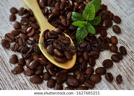 Wooden teaspoon between coffee beans, and mint leaves