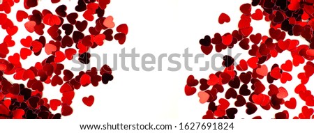 Red hearts are scattered on a bright background. Valentine's Day concept. Banner