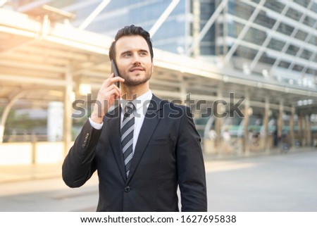 Close up of a caucasian business man using his phone for internet, messaging, call, texting and socializing, handsome looking and wearing a suit and tie within an urban city structure in background