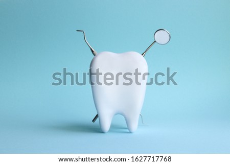 White tooth with dental instruments on a blue background in honor of the international day of the dentist on February 9 Royalty-Free Stock Photo #1627717768