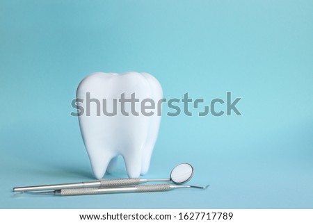 White tooth with dental instruments on a blue background in honor of the international day of the dentist on February 9 Royalty-Free Stock Photo #1627717789