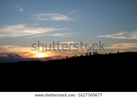 A silhouette picture of people on  mountain in sunset time.