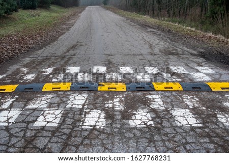 Black and yellow speed bump line  on concrete road surface. An old  traffic safety speed bump on a  road