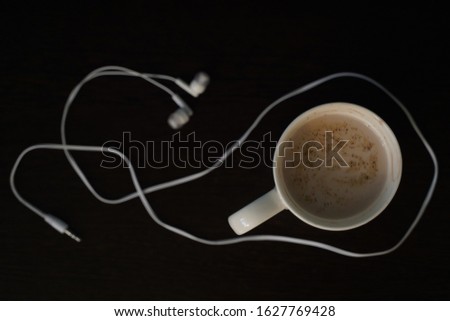 Flatley coffee and headphones on a black background. The concept of love for music, music to Wake up
