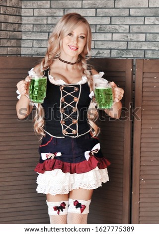 Beautiful woman in dress with a green irish beer posing on stone wall. Happy St. Patrick's Day.