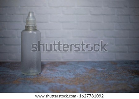 Transparent tube for cosmetics with a transparent cap on a wooden background against the background of a white brick wall