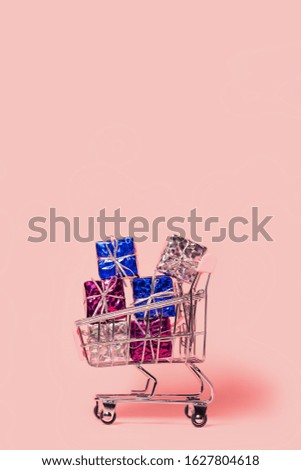 Small decorative trolley with present boxes on bright colorful background. Christmas or birthday gift. Sales and shopping concept.  Image is with copy space