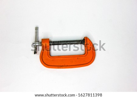 C-clamp in a horizontal close up photography. Image of orange tools isolated on white background.