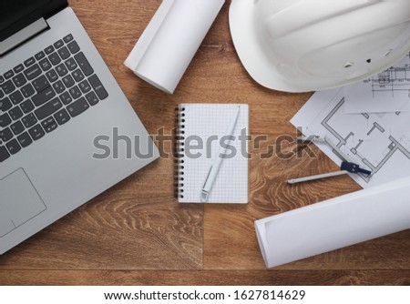 Creative layout of architects with roll drawings, architectural project plan, construction helmet on floor, workspace with laptop. Top view. Flat lay