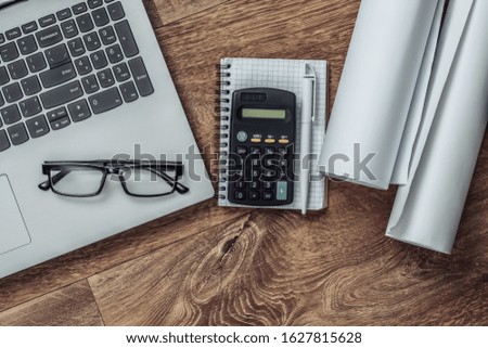 Creative layout of architects with roll drawings, architectural project plan, construction helmet on floor, workspace with laptop. Top view. Flat lay