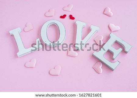Inscription LOVE in wooden letters on a pink background. Festive background to the day of lovers. The concept of congratulations on Valentine's Day. Copy space. Flatlay.