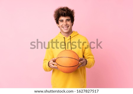 Young caucasian man over isolated pink background with ball of basketball
