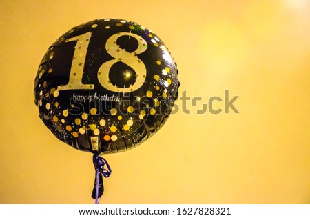 Balloon with number '18' in golden fonts and happy birthday's wishes in yellow background Royalty-Free Stock Photo #1627828321