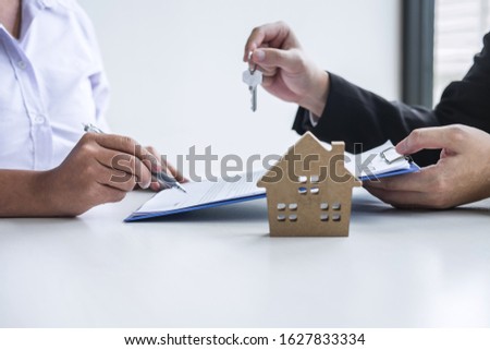 Estate agent giving house keys to client after signing agreement contract real estate with approved mortgage application form, concerning mortgage loan offer for and house insurance.