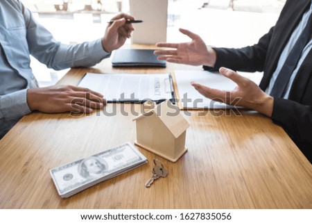 Real estate agent are presenting home loan and giving house, keys to customer after signing contract to buy house with approved property application form.