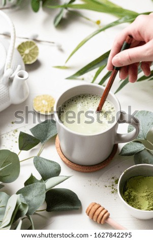 Green tea latte with green leaves and wooden spoon