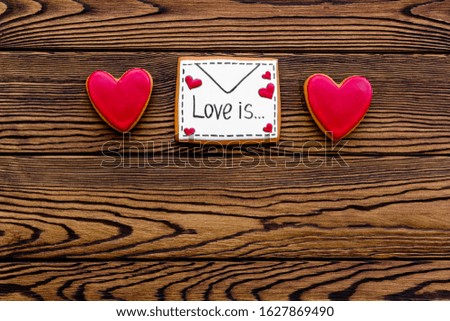 Valentine's Day. Gingerbread cookies in the shape of a red and white heart, 
with the image of a couple in love and a love letter. Gray marble background top view,flat lay, mockup