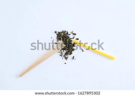 Cigarette paper with a filter and a plastic stick and a handful of tobacco on a white background.