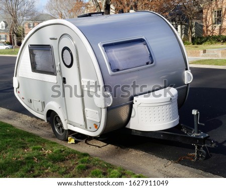 Cute teardrop shaped camping trailer parked in residential neighborhood. Royalty-Free Stock Photo #1627911049