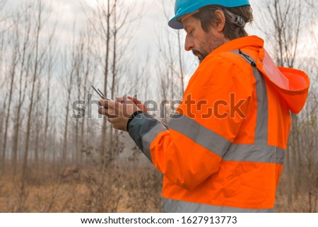 Forestry technician flying a drone with remote controller in woods and making aerial photos of forest