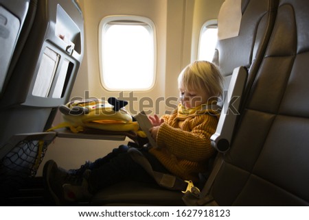 Blonde toddler boy, flying with airplane,enjoying the flight drawing