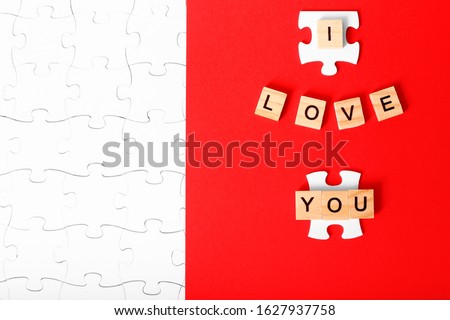 Greeting card for Valentine's Day. Puzzles as a symbol of love. Lovers like puzzles complementing each other.  Letters I love you. Red and white colours.
