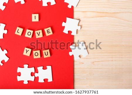 Greeting card for Valentine's Day. Puzzles as a symbol of love. Lovers like puzzles complementing each other.  Letters I love you. Red and white colours.