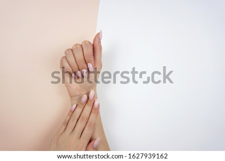 Beautiful female classic pink manicure. Young woman's hands on peach and white background.