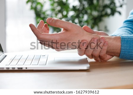 Close up of man arms holding his painful wrist caused by prolonged work on the computer, laptop. Carpal tunnel syndrome, arthritis, neurological disease concept. Numbness of the hand