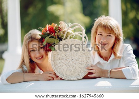 Elegant mother with young daughter. Family in a park. Women with a bouquet of flowers