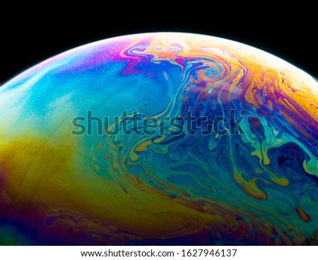 Colors and shapes created the surface of a soap bubble on black background.