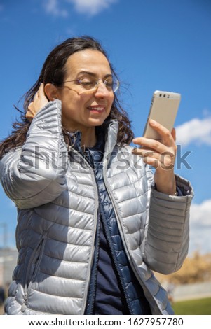 Pretty hispanic woman with mobile in a sunny day in outdoors