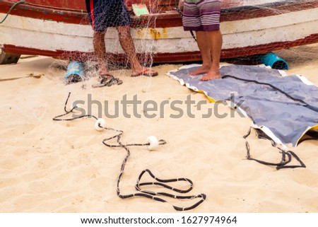 Fishermen preparing fishing nets in front of a boat at the Ingleses beach in the island of Florianópolis, Santa Catarina, Brazil.