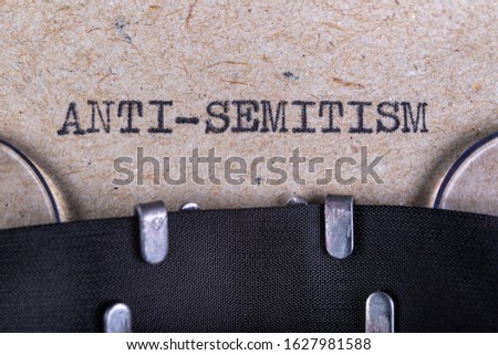 The word anti-semitism written in typewriter font. The inscription in the old style on gray paper. Grey background. Royalty-Free Stock Photo #1627981588