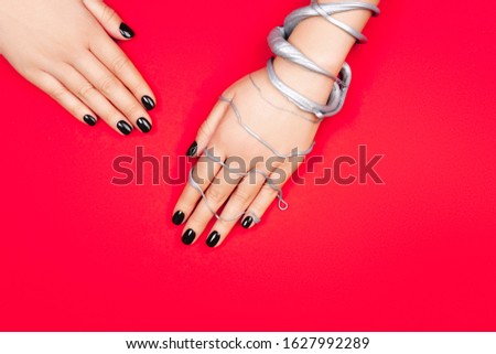 Black manicure on creative red and silver background. Flat lay style.