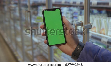 Lviv, Ukraine - May 19, 2018: On shop man hands holding use touch phone with horizontal green screen background busy finger touch message cellphone display girl slow motion